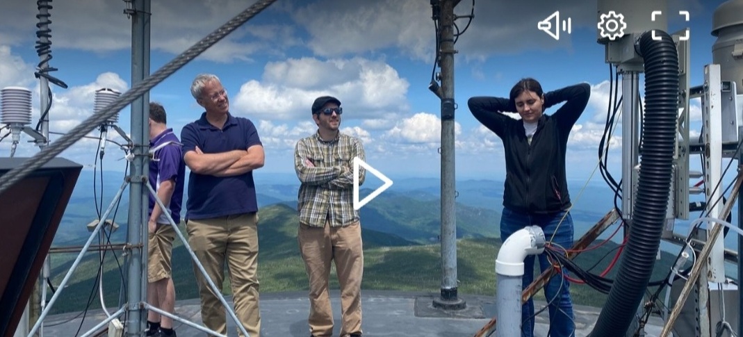 Screenshot of Spectrum News video player showing Adam Deitsch, Sara Lance, and others on top of the Whiteface Mountain Summit Observatory.