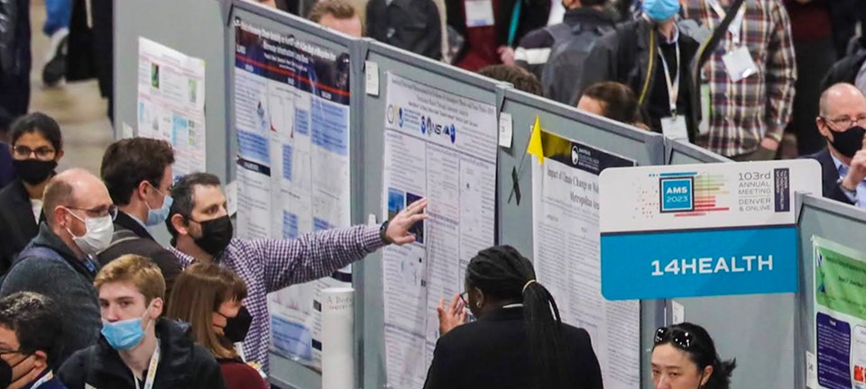 Wide-angle photograph of Adam presenting his poster to attendees at the AMS 103rd Annual Meeting.